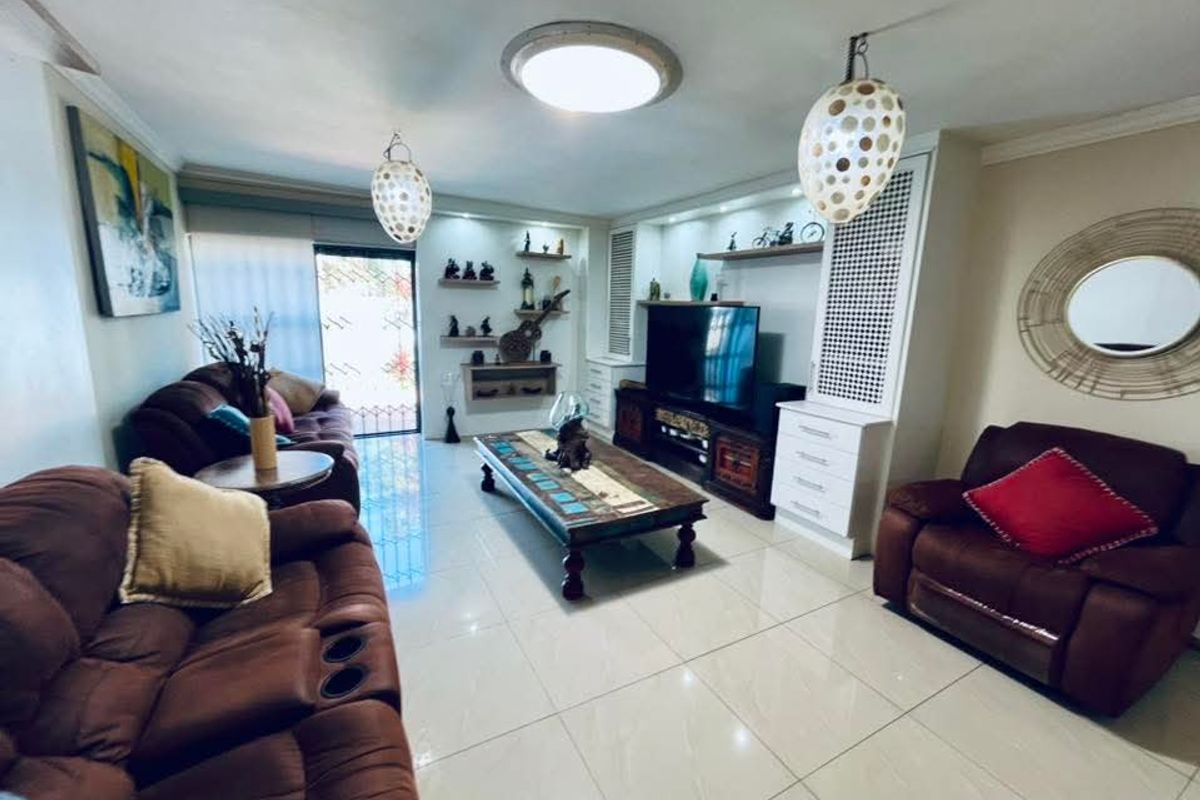 A comfortable living room featuring tiled flooring, built-in cabinetry with integrated shelving, and direct access to an outdoor area through a security gate.