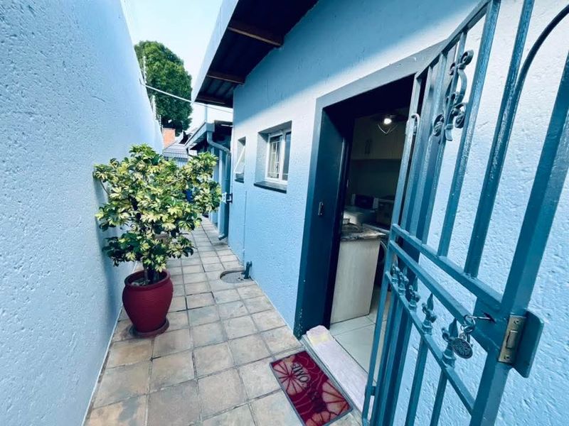 A narrow, paved exterior side walkway featuring a secure metal gate and access to the interior living space.