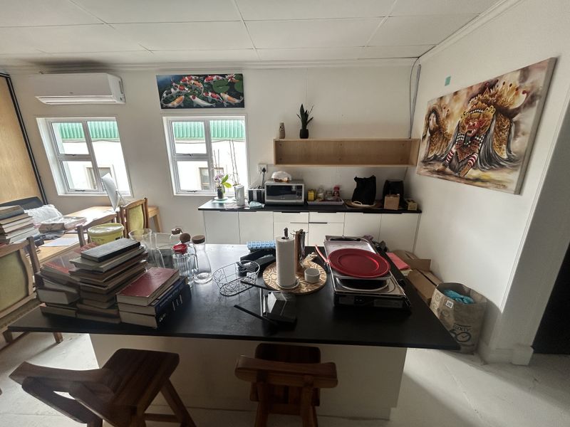 A functional kitchen area featuring built-in cabinetry, a central island, wall-mounted shelving, and a split-system air conditioner, providing a practical workspace.