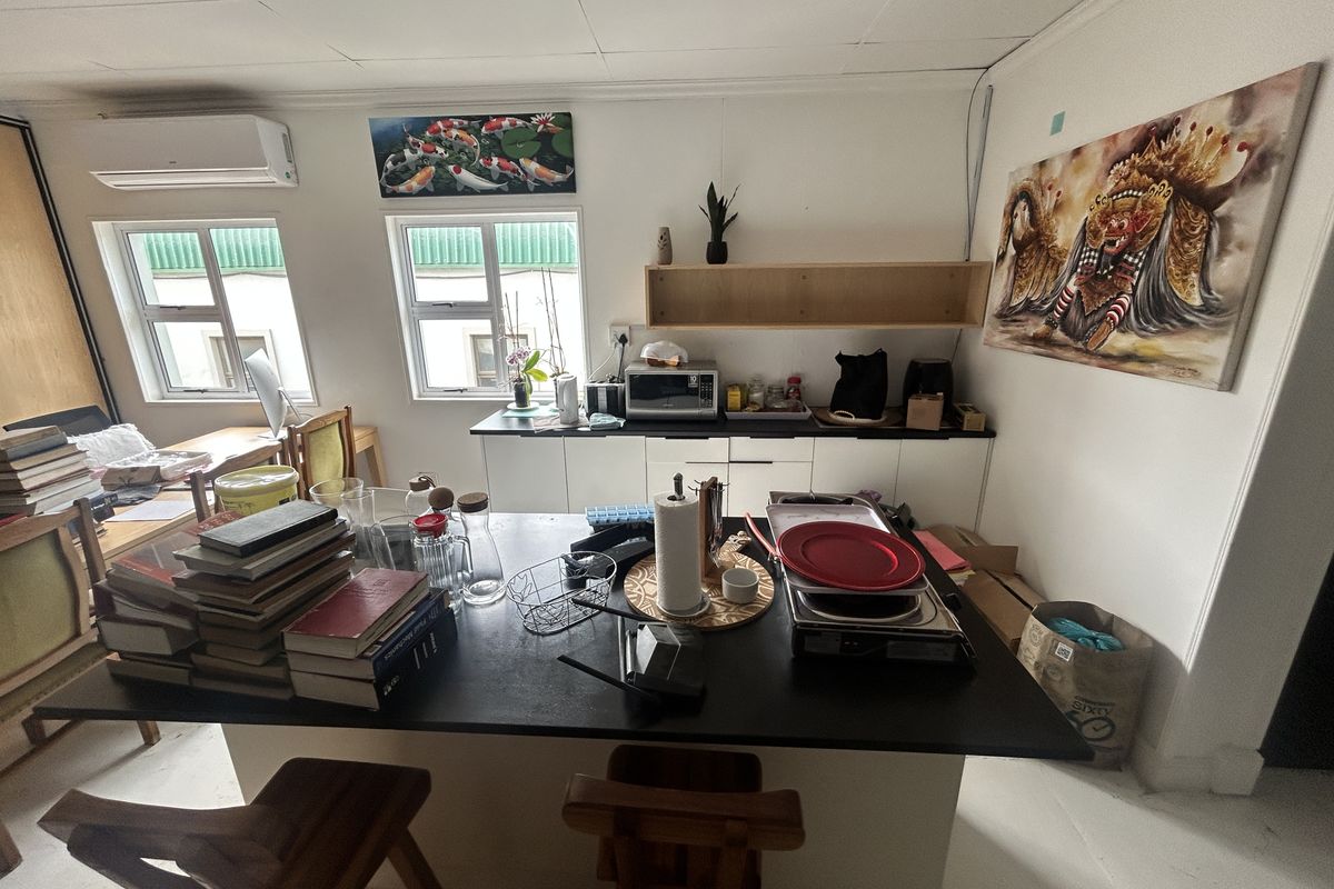 A functional kitchen area featuring built-in cabinetry, a central island, wall-mounted shelving, and a split-system air conditioner.