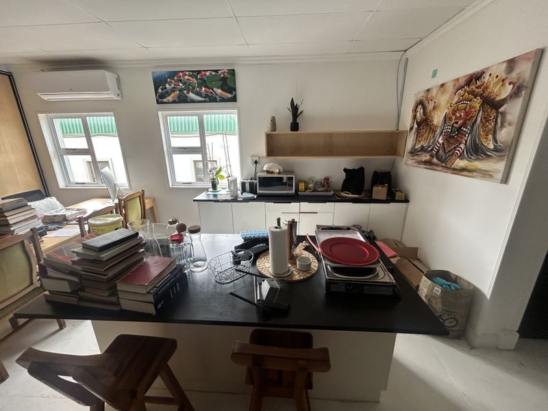 A functional kitchen area featuring built-in cabinetry, a central island, wall-mounted shelving, and a split-system air conditioner.