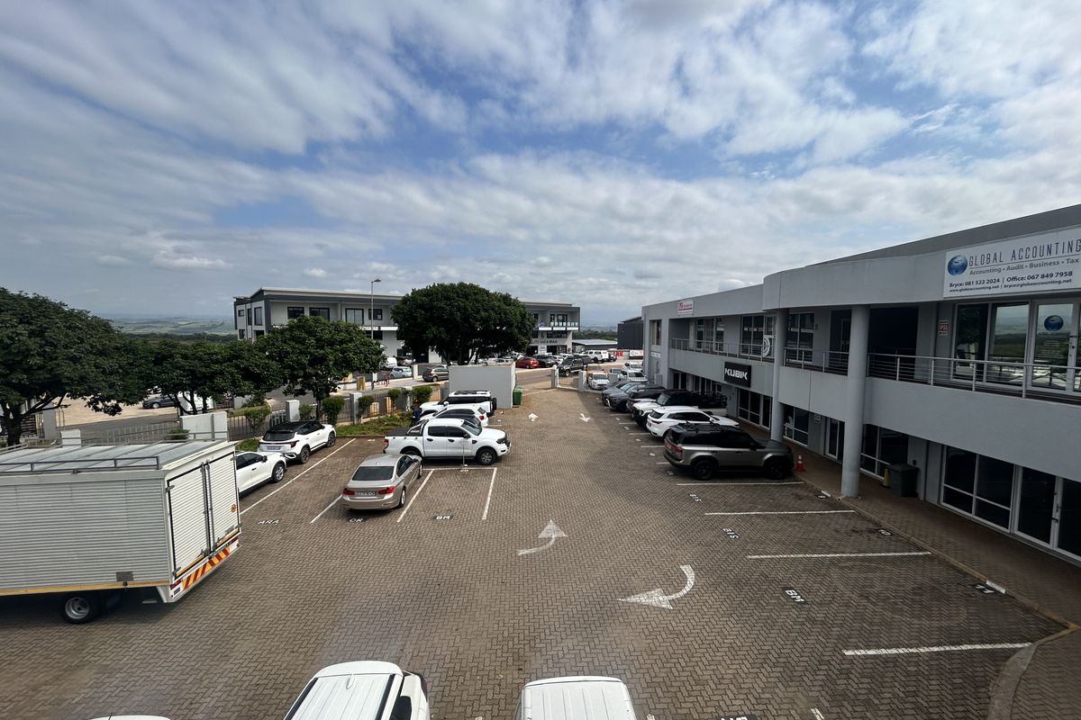 An elevated view of a commercial office complex featuring a paved parking lot and multi-level building facades with balcony access.