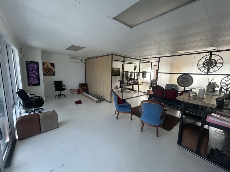 Open plan office space featuring glass partition walls, suspended ceiling tiles, and an integrated air conditioning unit.