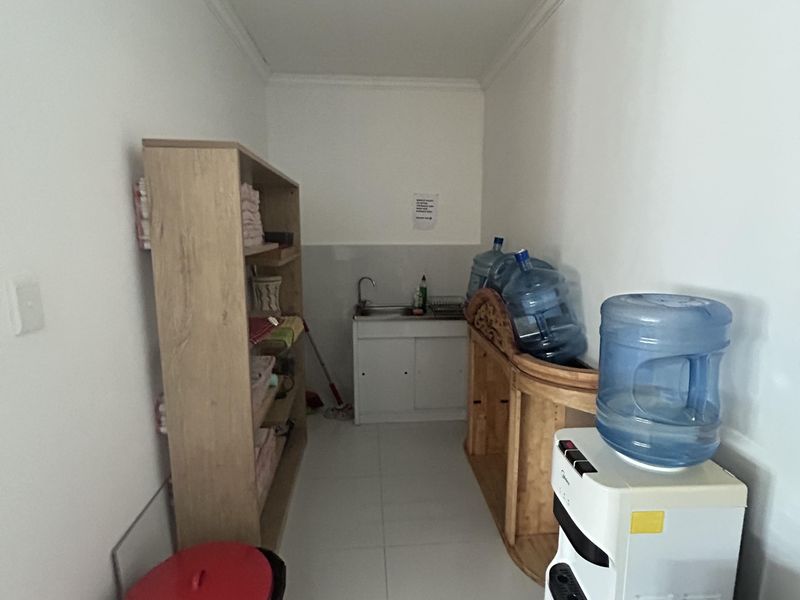 A functional utility space featuring tiled flooring, a built-in sink, and coved ceiling detailing, suitable for storage or preparation tasks.