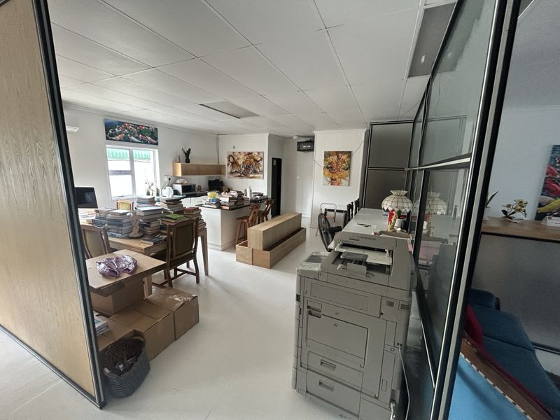 Open-plan office space featuring a suspended ceiling, glass partition walls, and a small built-in kitchenette area.