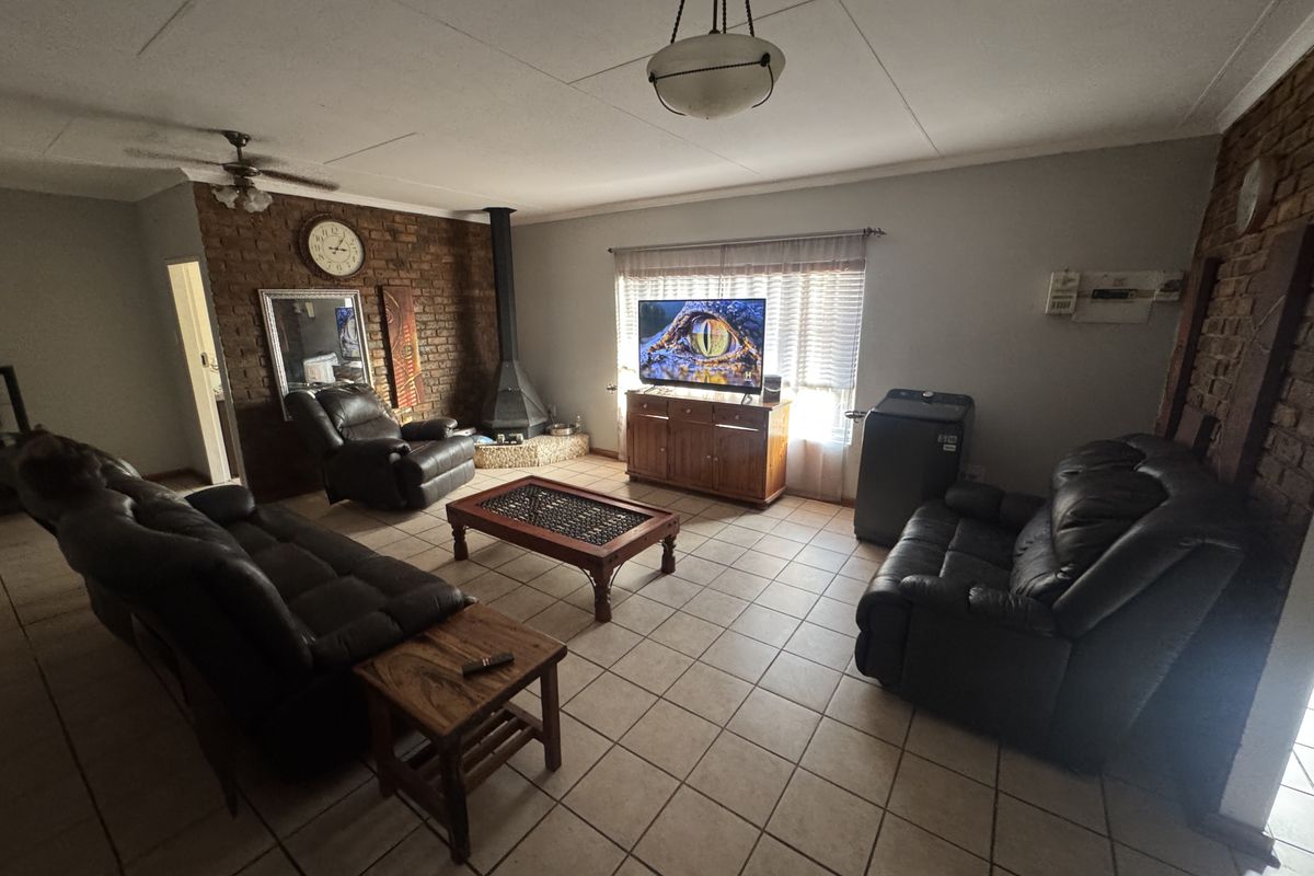 Spacious living room featuring a prominent brick feature wall, a built-in fireplace, and tiled flooring throughout.
