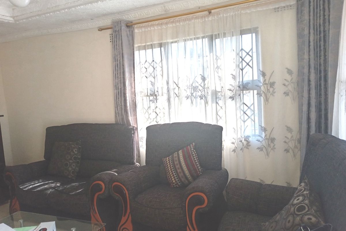 A living room featuring decorative ceiling molding and a large window with security bars, providing natural light to the space.
