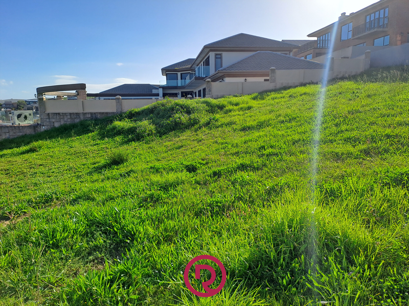 A sloped residential vacant land plot featuring established boundary walls and views of neighboring properties.