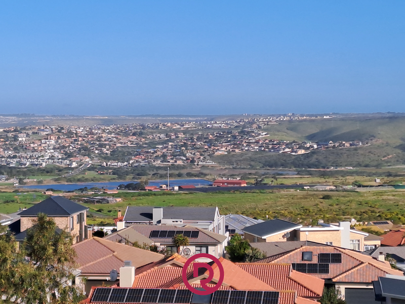 Elevated panoramic view overlooking a residential neighborhood, surrounding landscape, and distant coastal terrain.