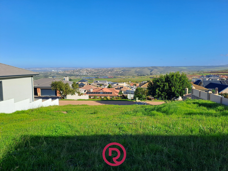 A scenic elevated view overlooking a residential neighborhood and surrounding landscape from a vacant residential plot.