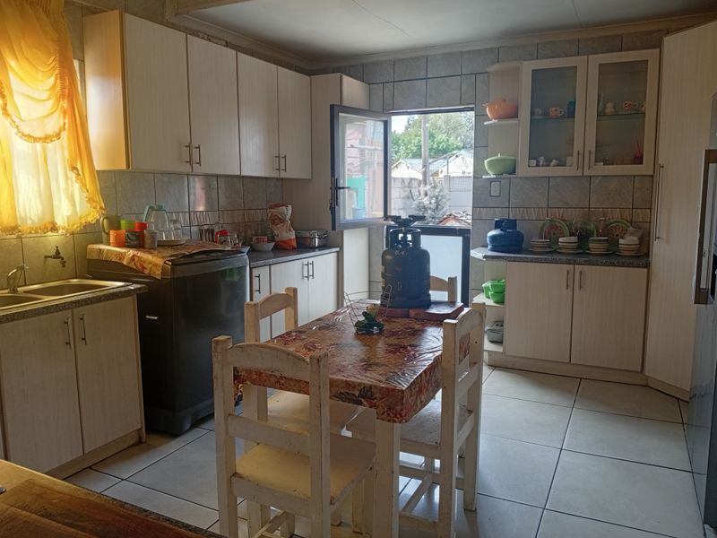 A functional kitchen featuring laminate cabinetry, tiled backsplash, and ceramic flooring, offering a practical layout with direct access to the exterior.