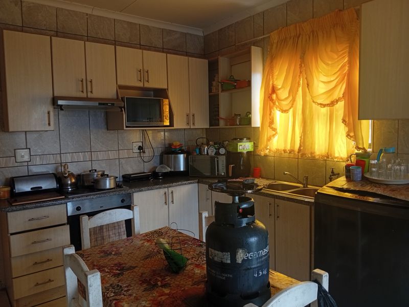 A functional kitchen featuring built-in cabinetry, laminate countertops, a double bowl sink, and integrated oven with extractor fan, requiring cosmetic updates.