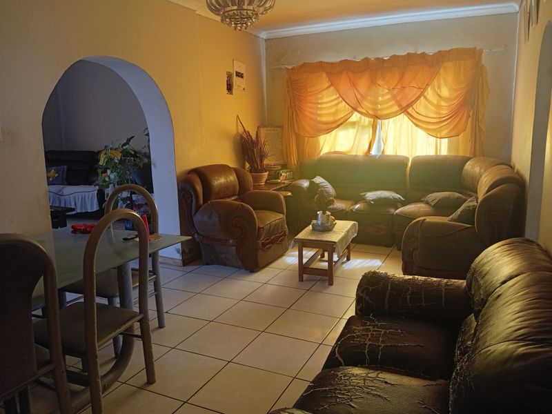 A living room featuring tiled flooring, a decorative archway, and coved ceilings, with visible signs of wear on the wall finishes.