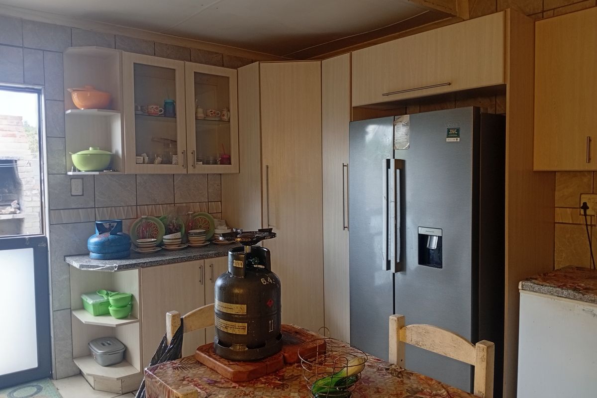 A functional kitchen featuring built-in cabinetry, tiled backsplash, and space for a large refrigerator, offering a practical layout for daily meal preparation.