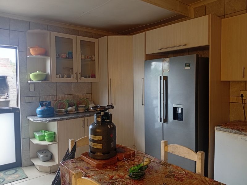 A functional kitchen featuring built-in cabinetry, tiled backsplash, and space for a large refrigerator, offering a practical layout for daily meal preparation.