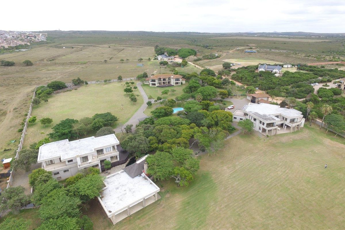 An aerial view of a large estate featuring multiple residential buildings, expansive landscaped grounds, mature trees, and a swimming pool in a rural setting.