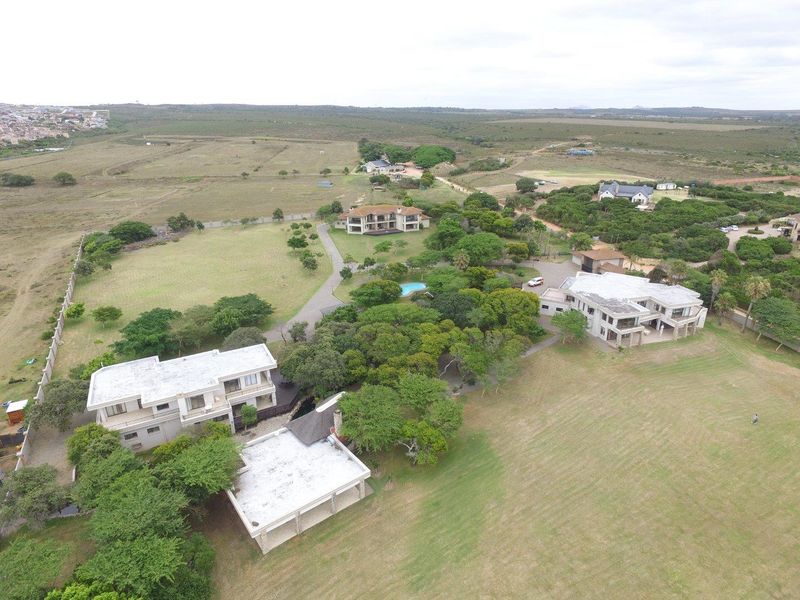 An aerial view of a large estate featuring multiple residential buildings, expansive landscaped grounds, mature trees, and a swimming pool in a rural setting.