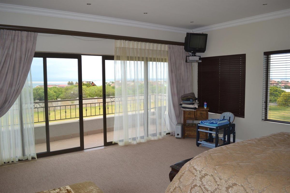 Spacious bedroom featuring large sliding glass doors that open onto a private balcony with scenic views and integrated downlighting.
