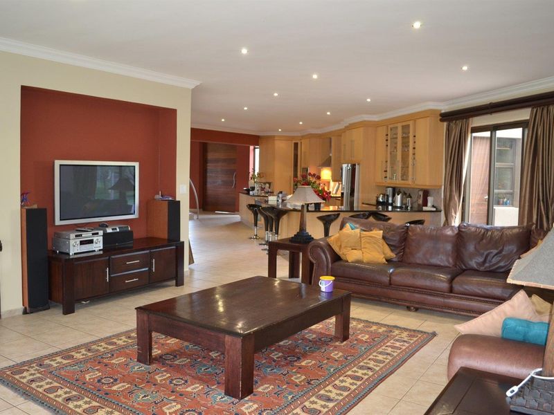 Open-plan living area featuring a kitchen with wooden cabinetry and a spacious lounge area with tiled flooring and recessed lighting.
