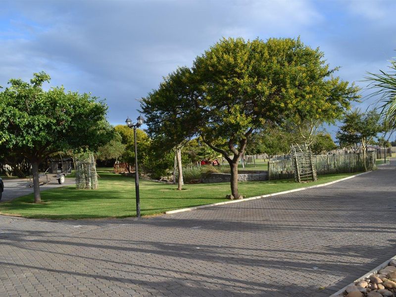 A well-maintained garden area featuring paved pathways, mature trees, and manicured lawn space within the property grounds.