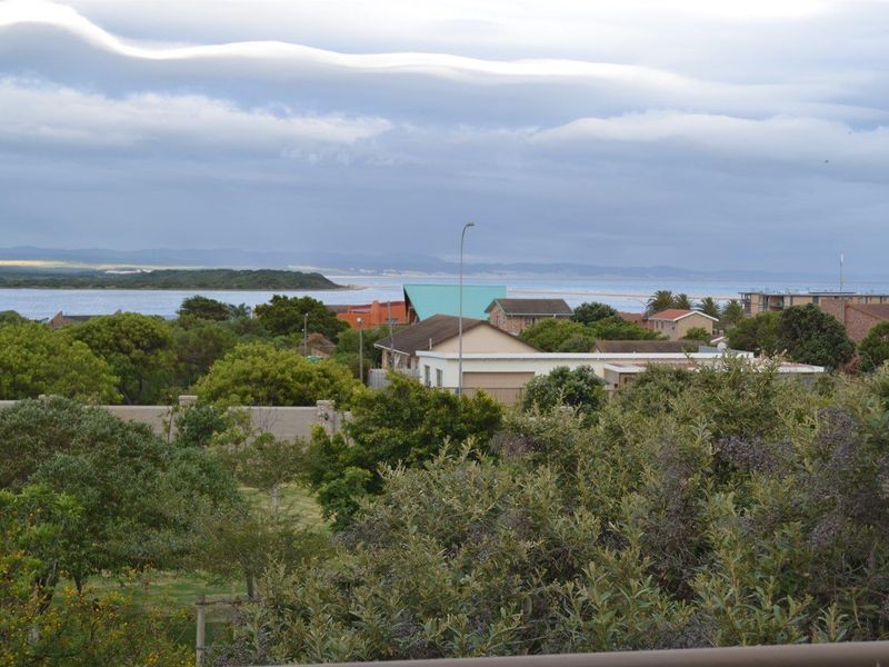 A scenic elevated view overlooking the surrounding coastal neighborhood, lush greenery, and the distant lagoon and coastline.