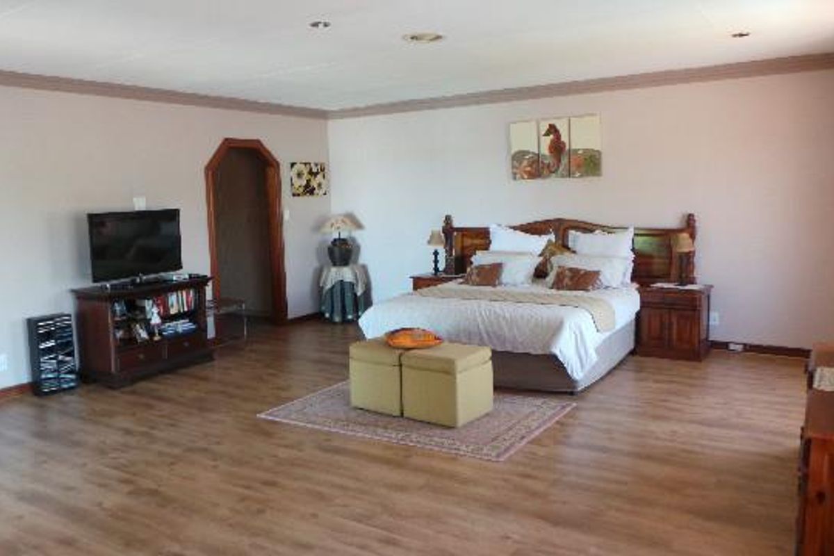 Spacious bedroom featuring wood-look laminate flooring, recessed ceiling lighting, and arched doorways leading to adjacent rooms.