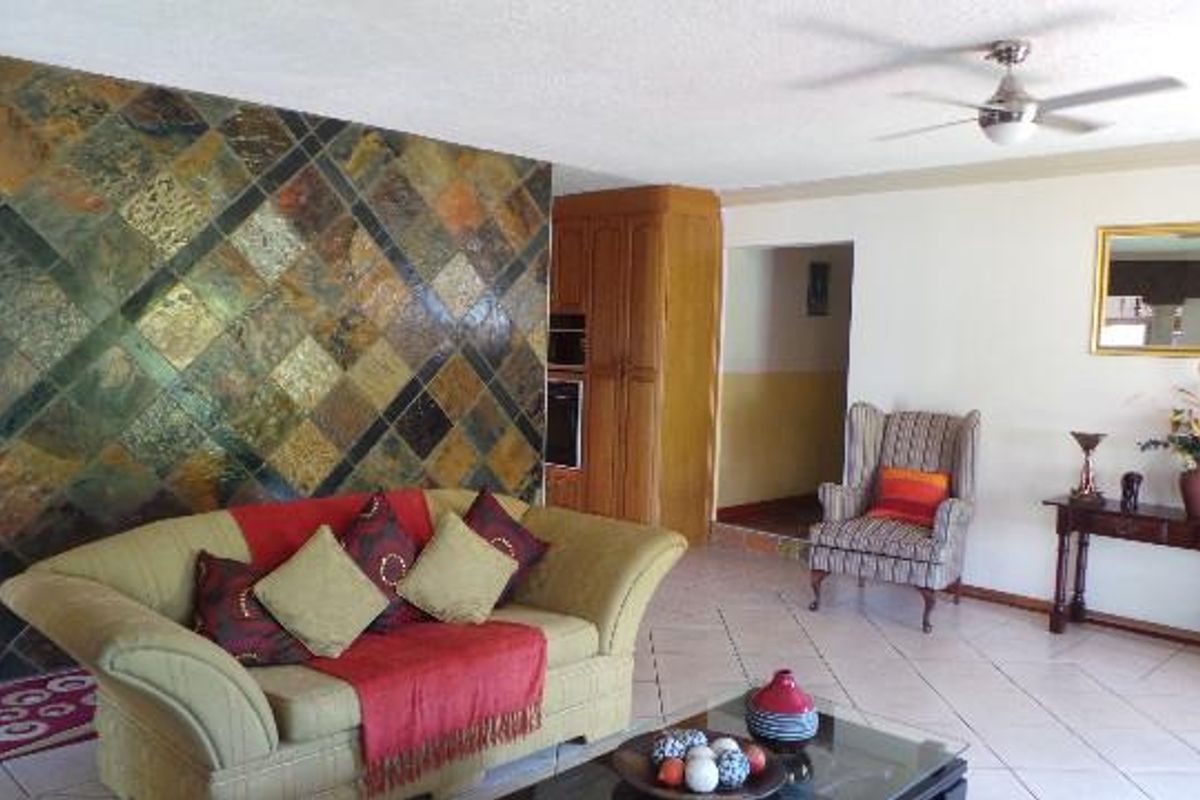 Spacious living area featuring a prominent decorative slate-tiled feature wall, ceramic floor tiles, and a ceiling fan.