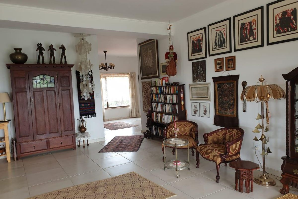 A spacious living area featuring tiled flooring, neutral walls, and an open-plan layout leading to an adjacent room.