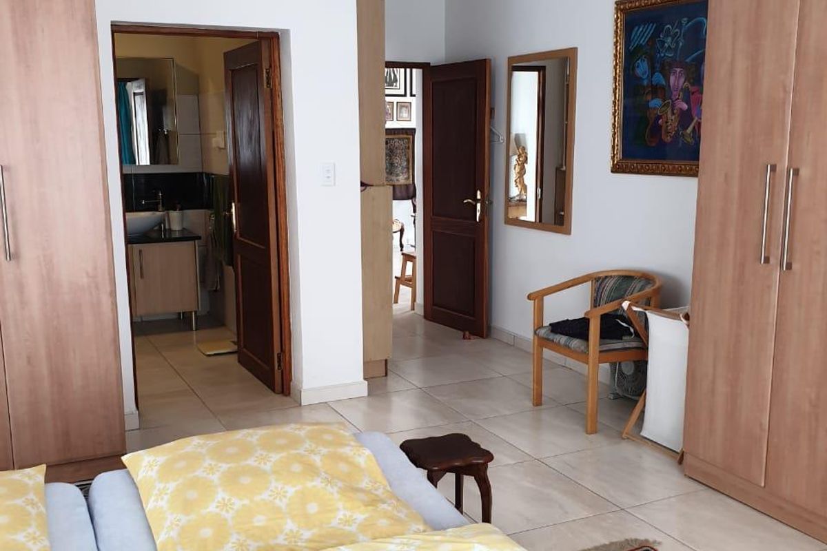A bedroom featuring built-in wooden wardrobes, tiled flooring, and direct access to an en-suite bathroom.