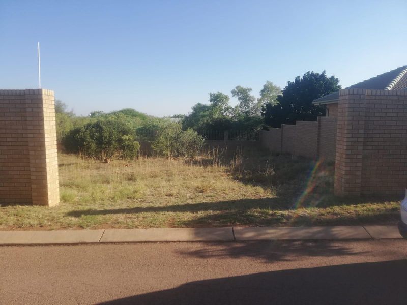 A vacant residential plot featuring brick boundary walls and pillars, offering a clear street-facing entrance and level ground for future development.