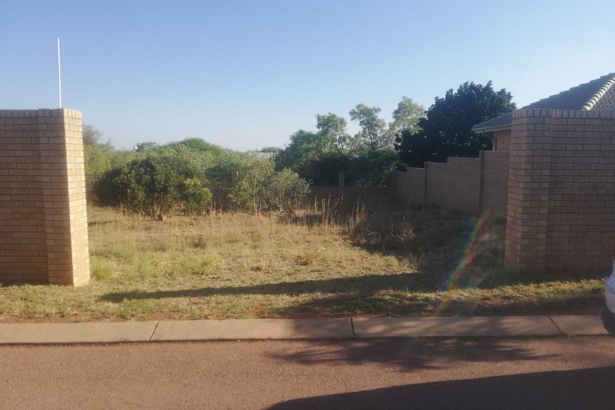 A vacant residential plot featuring brick boundary walls and pillars, offering a clear street-facing entrance and level ground for future development.