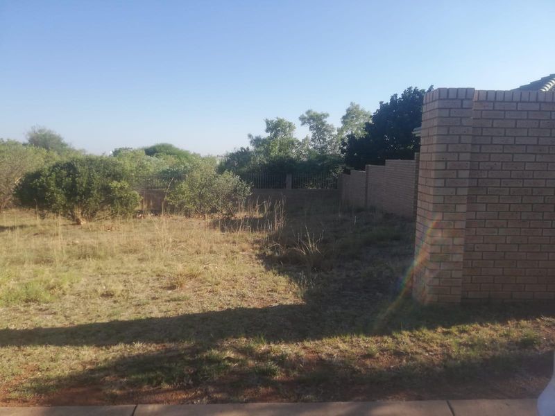 A view of the rear yard area featuring a brick boundary wall and established perimeter fencing on a vacant residential plot.