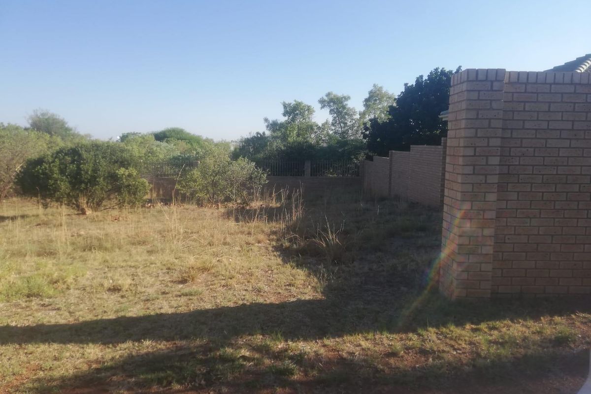 A view of the rear yard area featuring a brick boundary wall and established perimeter fencing on a vacant residential plot.