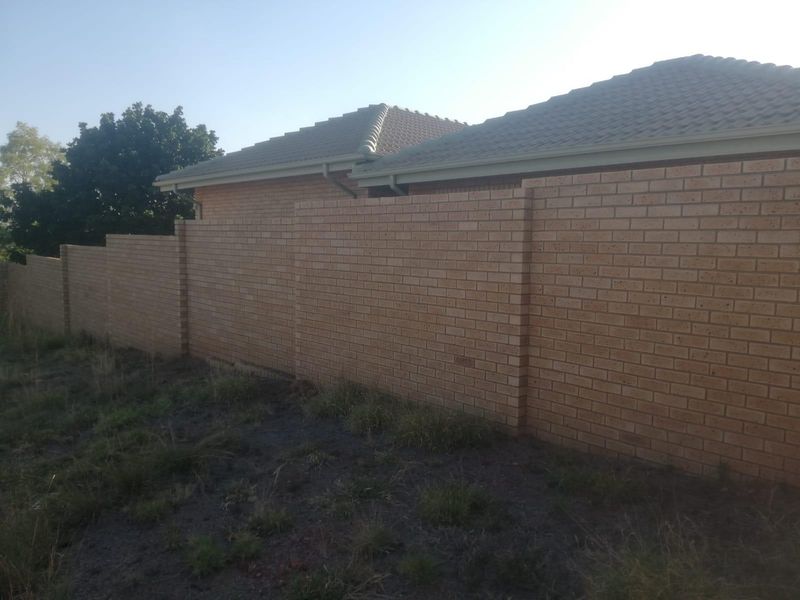 A view of a residential property boundary featuring a well-maintained brick wall and tiled roof structure.