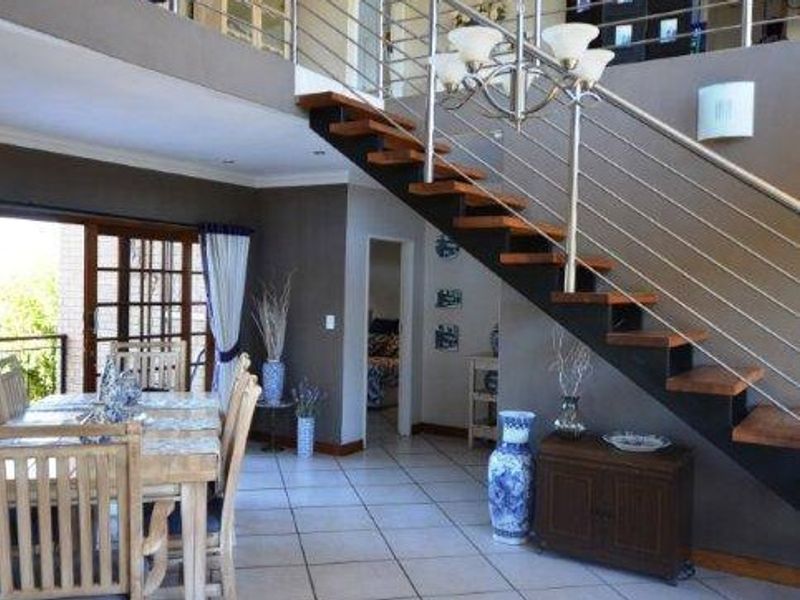 Open-plan living area featuring a modern open-tread staircase with stainless steel balustrades, tiled flooring, and large sliding doors leading to an outdoor space.