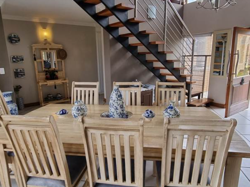 Dining area featuring an open-tread staircase with metal railings, tiled flooring, and direct access to the entrance.