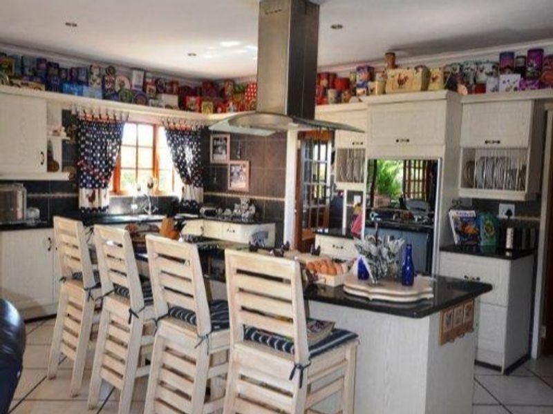 A functional kitchen featuring a central island with granite countertops, built-in cabinetry, and a stainless steel extractor fan, offering a classic layout.