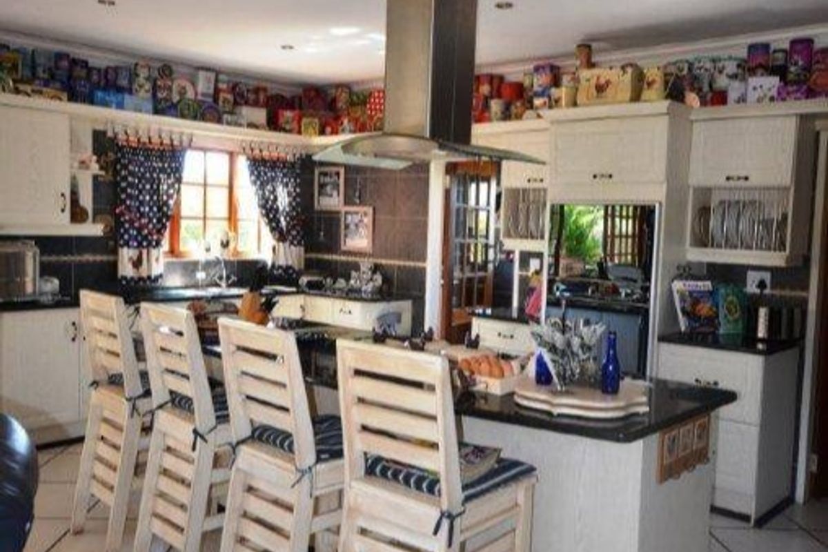 A functional kitchen featuring a central island with granite countertops, built-in cabinetry, and a stainless steel extractor fan, offering a classic layout.