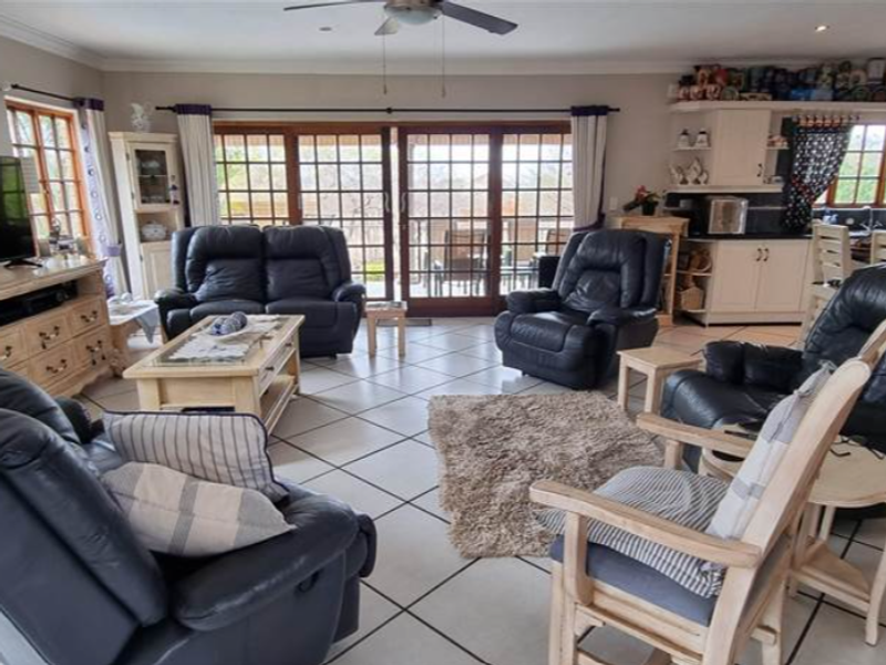 Spacious open-plan living and kitchen area featuring tiled flooring, a ceiling fan, and large sliding glass doors providing access to the outdoor space.