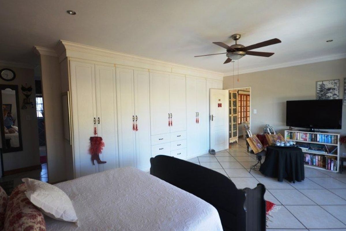 Spacious bedroom featuring extensive built-in cabinetry, tiled flooring, and a ceiling fan, offering ample storage and a functional layout.