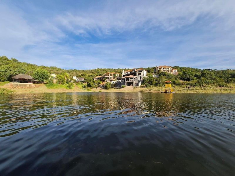 A scenic view of residential properties situated along the waterfront, showcasing the natural landscape and estate setting.