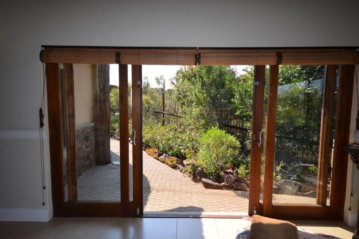A bright living area featuring large timber sliding doors that open onto a paved patio and landscaped garden.