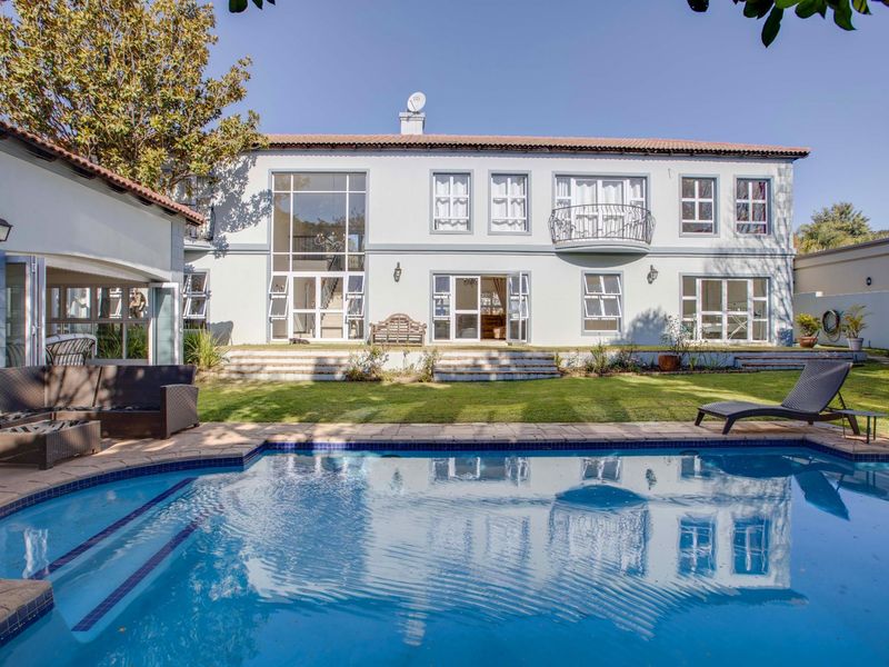 Spacious rear exterior featuring a well-maintained swimming pool, landscaped garden, and a large double-storey residence with classic architectural detailing and multiple access points.