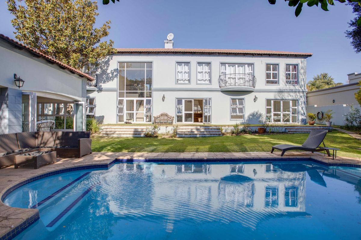 Spacious rear exterior featuring a well-maintained swimming pool, landscaped garden, and a large double-storey residence with classic architectural detailing and multiple access points.