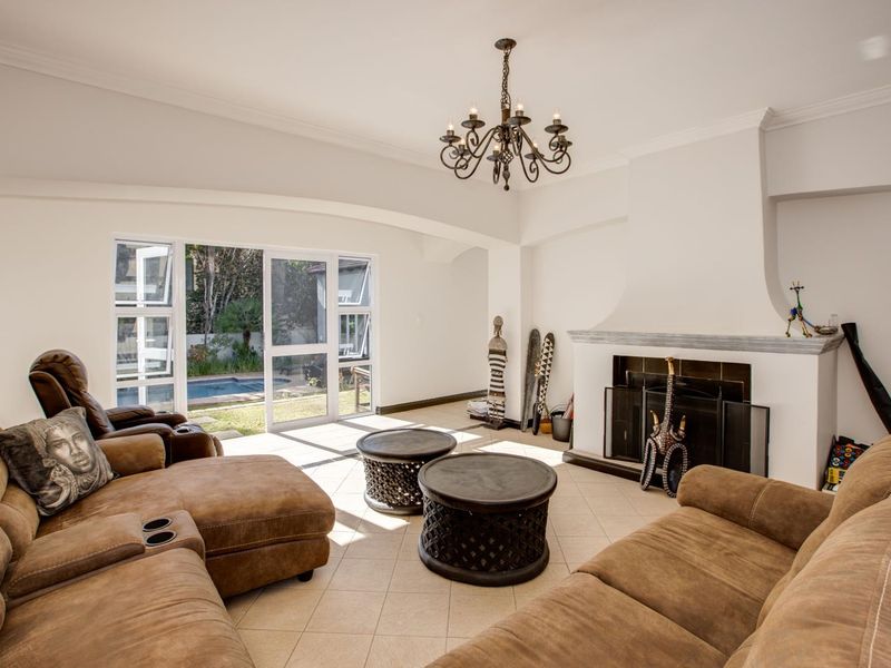 Spacious living room featuring a traditional fireplace with a mantelpiece, tiled flooring, and large sliding glass doors providing access to the garden and pool area.