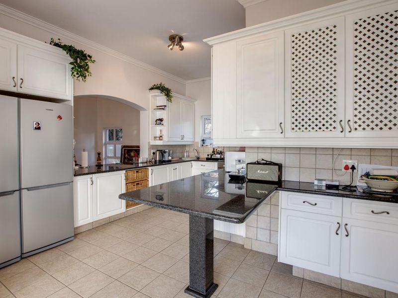 A well-maintained kitchen featuring white cabinetry, granite countertops, a breakfast bar, and neutral ceramic tile flooring.