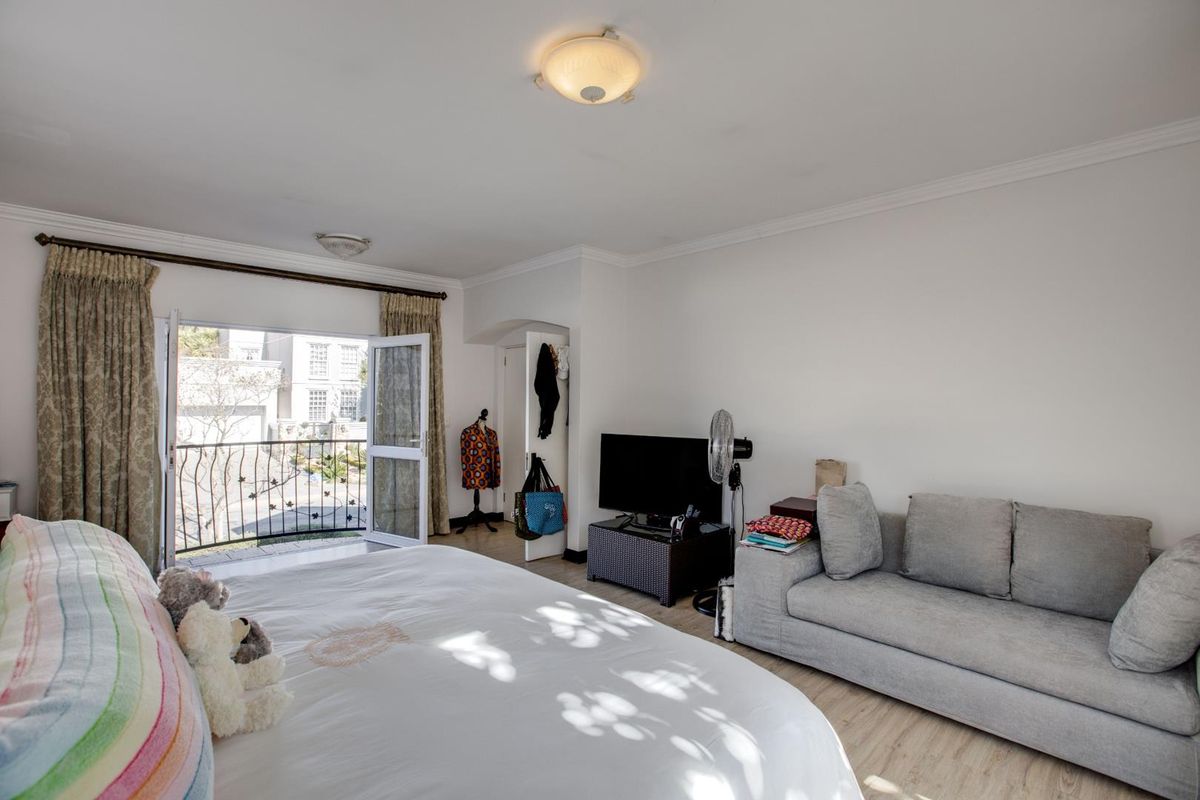 Spacious bedroom featuring laminate flooring, a ceiling light fixture, and direct access to a private balcony with wrought iron railings.