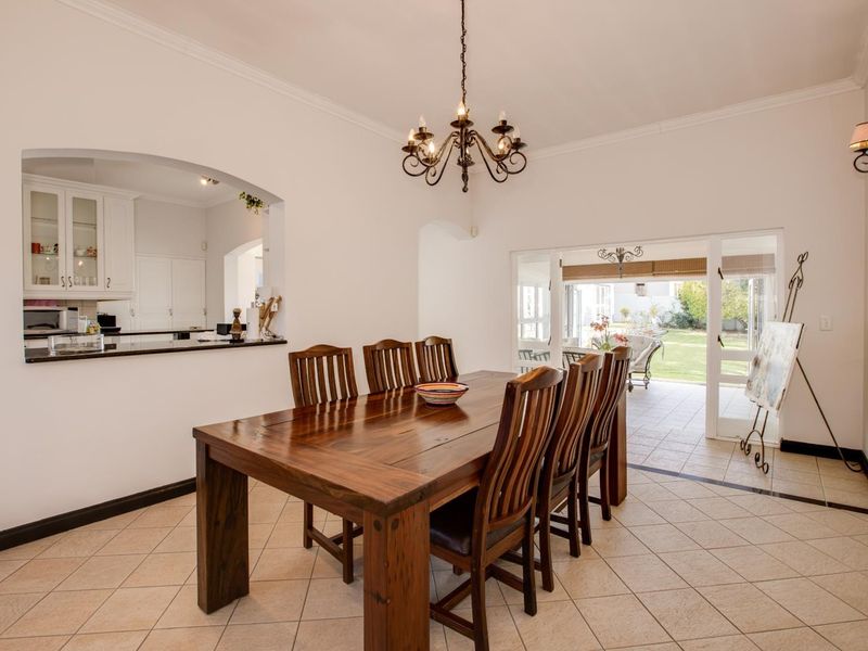 Spacious dining room featuring tiled flooring, a decorative chandelier, and an open pass-through to the kitchen with direct access to the patio.