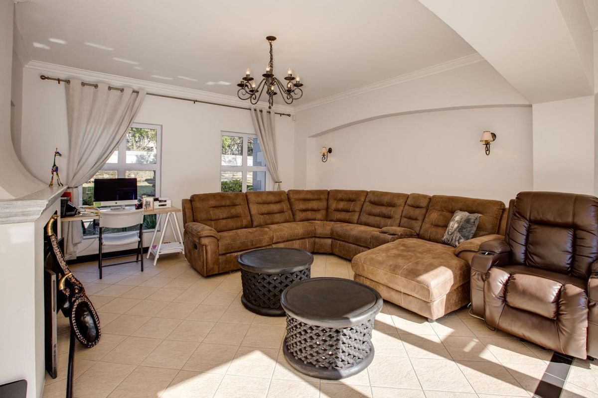 Spacious living room featuring tiled flooring, a fireplace, elegant crown molding, and a classic chandelier, creating a warm and inviting atmosphere.