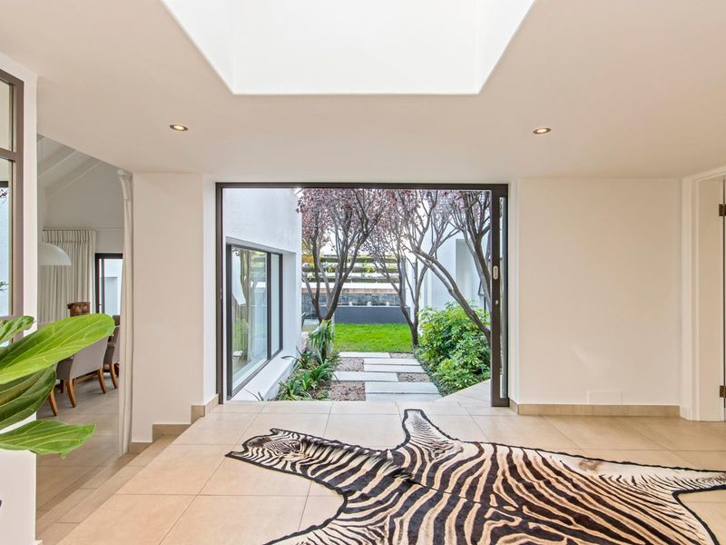 Bright living area featuring a large skylight, tiled flooring, and seamless access to the rear garden through expansive sliding glass doors.